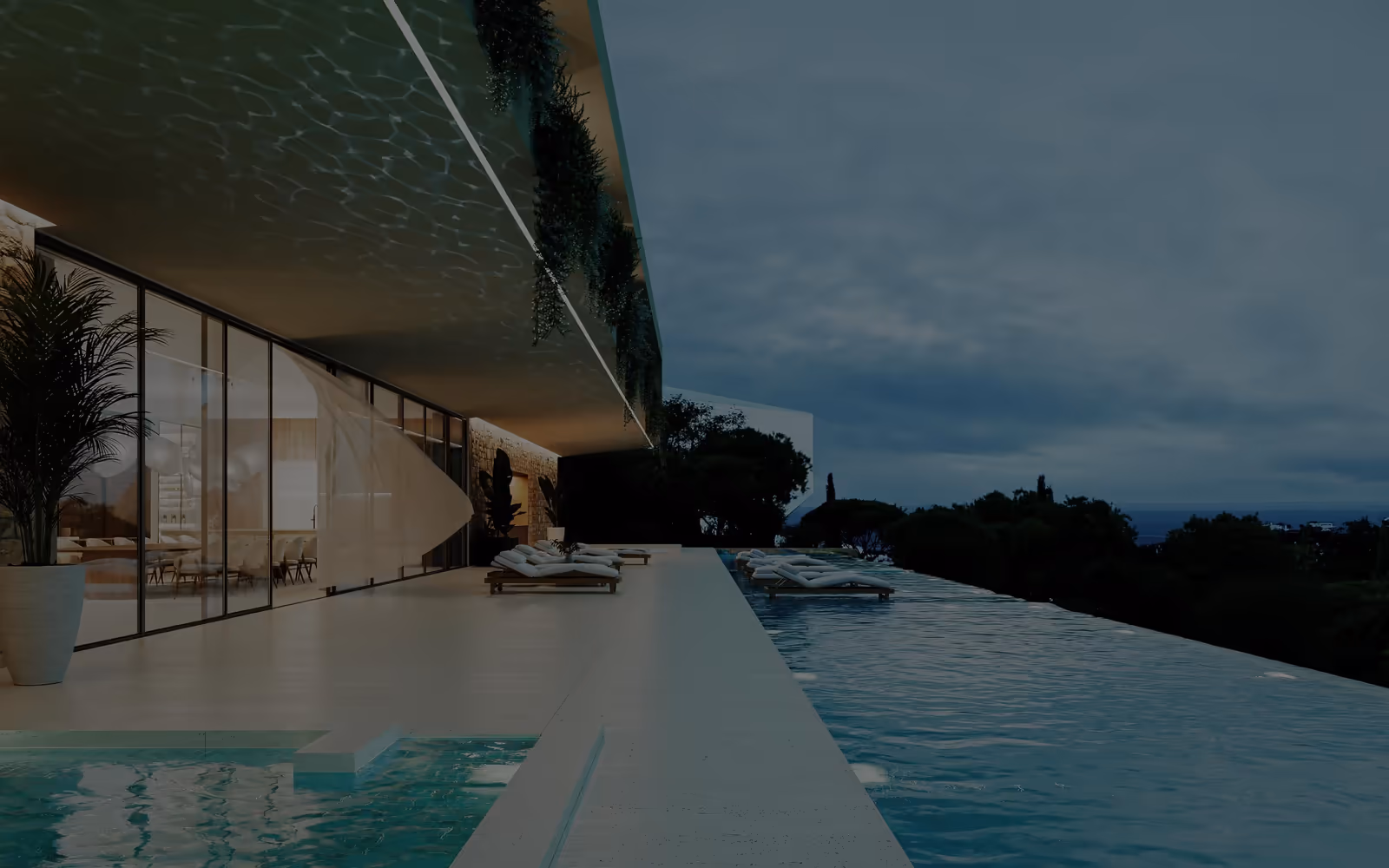 Ao anoitecer, uma piscina ao longo de um volume baixo e envidraçado com uma pala profunda, o mar ao fundo.