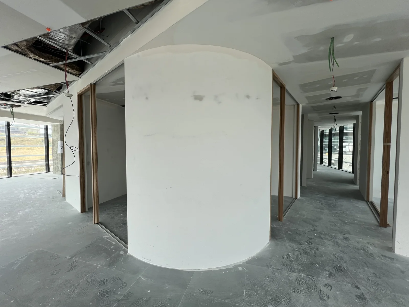A parede curva acabada em estuque branco, com um corredor de vãos emoldurados a passar ao lado.