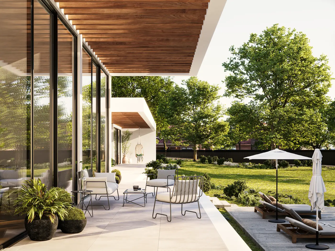 Um terraço coberto ao longo de uma fachada envidraçada, com assentos exteriores, um chapéu e relvado em frente.