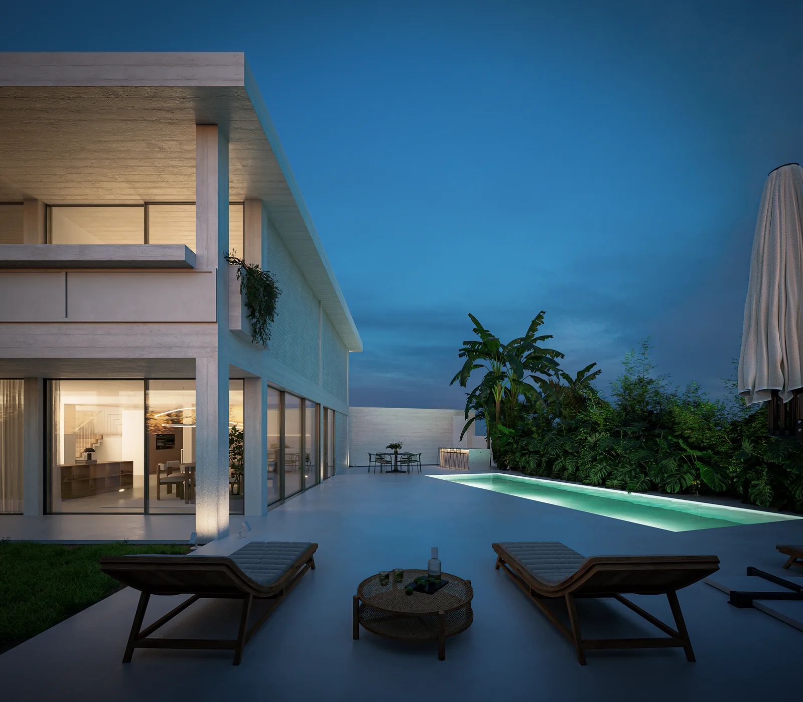 O mesmo terraço ao anoitecer, a piscina iluminada por dentro e o interior visível através do envidraçado de pé-direito completo, com a galeria superior em sombra por cima.